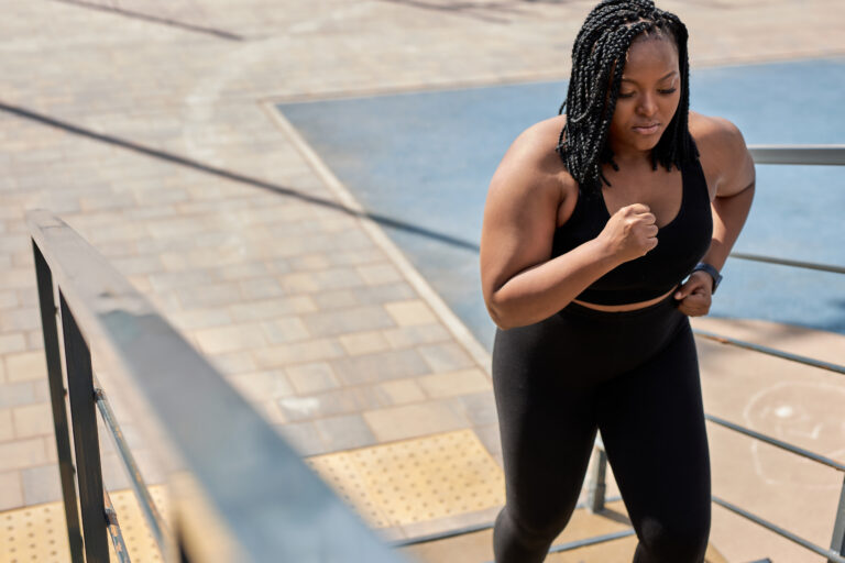 obese young african woman foing fitness exercises on stairs outdoors